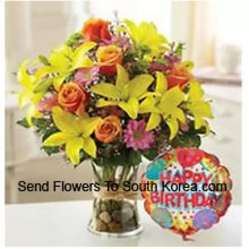 Tulipes jaunes, roses oranges et autres fleurs assorties parfaitement arrangées dans un vase en verre accompagnées d'un ballon d'anniversaire