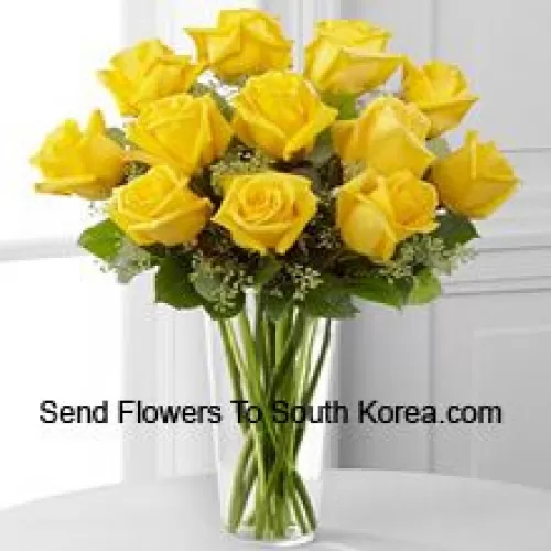 12 roses jaunes avec quelques fougères dans un vase en verre