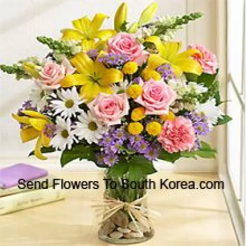 Roses roses, Oeillets roses, Géraniums blancs et Lys jaunes avec des remplissages saisonniers dans un vase en verre