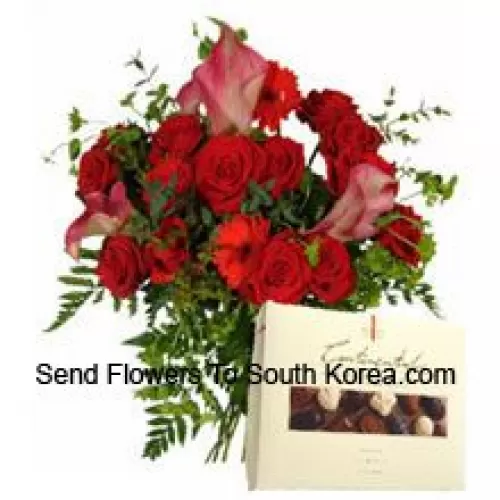 Gérberas rouges et roses dans un vase accompagnés d'une boîte de chocolats