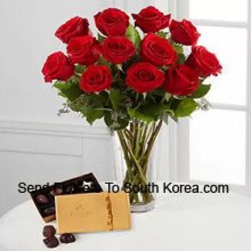 12 Roses rouges avec des fougères dans un vase et une boîte de chocolats Godiva (Nous nous réservons le droit de substituer les chocolats Godiva par des chocolats de valeur équivalente en cas de non disponibilité des mêmes. Stock limité)